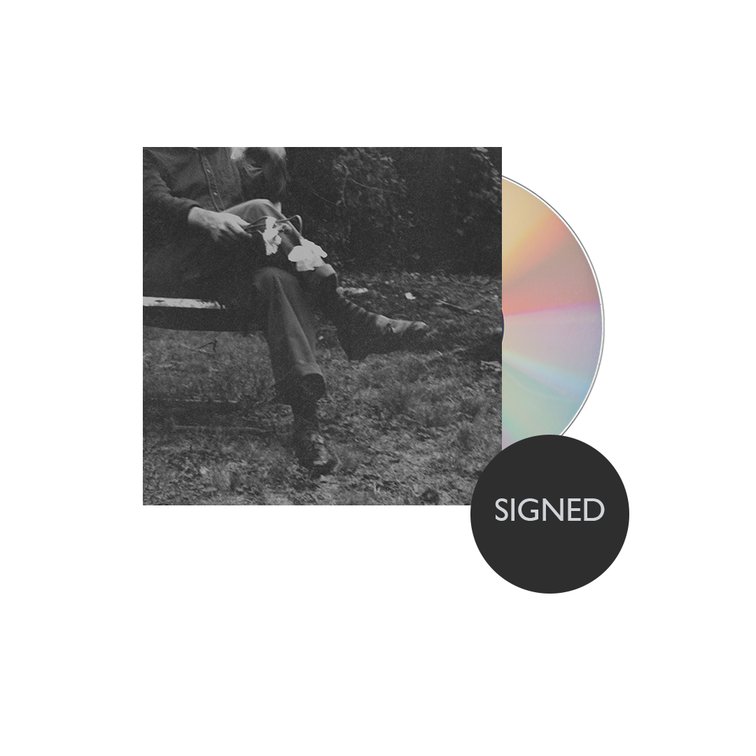 Album cover with a black and white photo of a person sitting outdoors and a colorful CD on a white background.