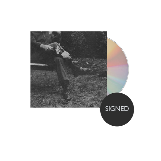 Album cover with a black and white photo of a person sitting outdoors and a colorful CD on a white background.